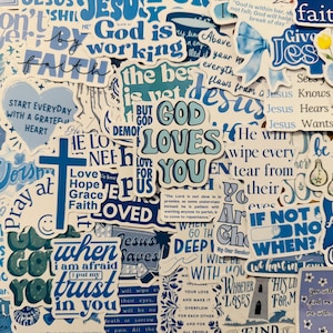 Può includere: Una collezione di adesivi blu e bianchi con citazioni e frasi religiose. Gli adesivi presentano frasi come "Dio ti ama", "Gesù" e "Fede". Varie forme e dimensioni, con una croce, un cuore e mani in preghiera.