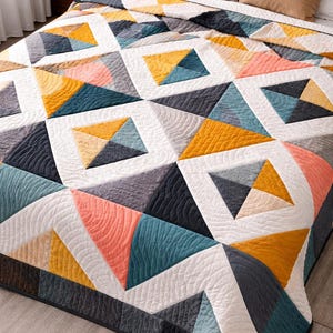 May include: A geometric quilt in shades of white, gray, teal, coral, and yellow. The quilt features a repeating pattern of triangles and squares, creating a modern and colorful design. The quilt is on a bed with pillows.