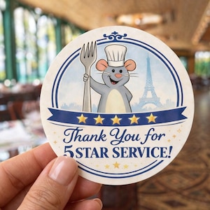 May include: A set of three ceramic mugs with a speckled, cream-colored glaze. Each mug features a different hand-painted design: a blue and green leaf, a yellow flower, and a red berry. The mugs have a simple, rounded shape.