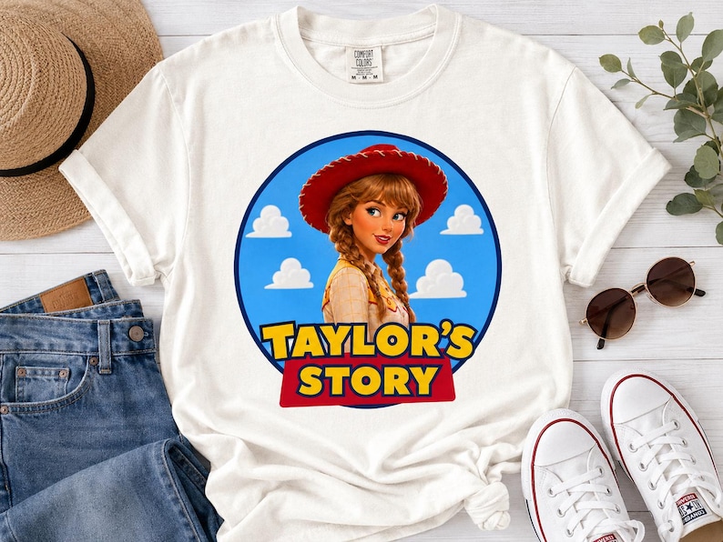 Puede incluir: Una camiseta blanca de manga corta con un gr&aacute;fico circular de un personaje de dibujos animados con trenzas y un sombrero de vaquero rojo. El fondo es azul con nubes blancas. El texto "TAYLOR'S STORY" est&aacute; impreso en letras amarillas y rojas.