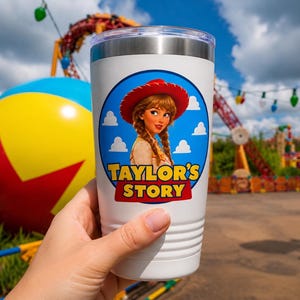 May include: A white stainless steel tumbler with a clear lid featuring a circular graphic of a person with braided hair wearing a red cowboy hat. The text "TAYLOR'S STORY" is printed in yellow with a red outline inside the blue circular design.