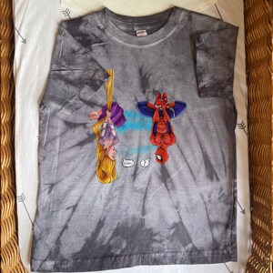 May include: Gray tie-dye t-shirt featuring cartoon illustrations of Rapunzel and Spider-Man hanging upside down. Rapunzel is wearing a purple dress and Spider-Man is in his classic red and blue suit. Speech bubbles include "Oh Hai!" and a question mark.