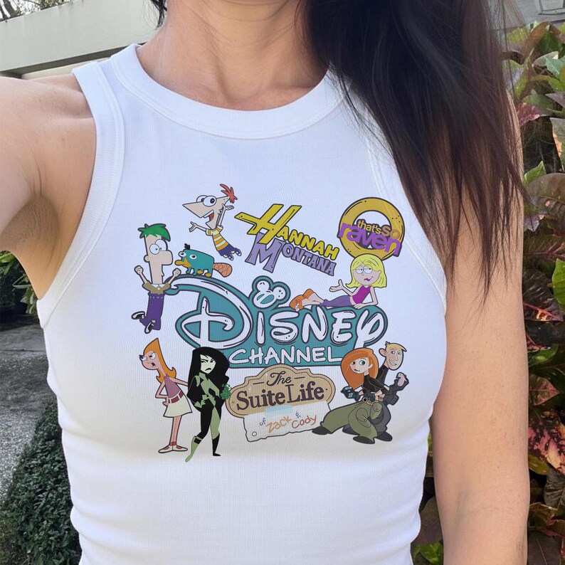 May include: White ribbed vest top with a colourful Disney Channel graphic. The graphic includes characters and logos from various Disney shows, such as Hannah Montana, Kim Possible, and The Suite Life of Zack & Cody.