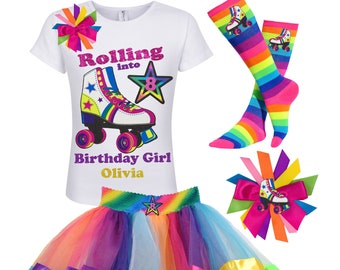 May include: A white t-shirt with a rainbow roller skate graphic and the text "Rolling into 8 Birthday Girl Olivia". A rainbow tutu with a star and the number 8 on the waistband. A rainbow striped pair of socks with a roller skate graphic. A rainbow bow with a roller skate graphic.