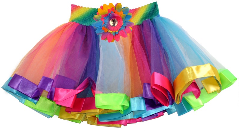 May include: A rainbow tulle skirt with a colourful flower accent and multiple layers of satin ribbon trim.