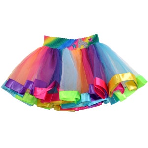 May include: A rainbow tulle skirt with a colorful waistband and a star design. The skirt has multiple layers of tulle and is trimmed with satin ribbon.