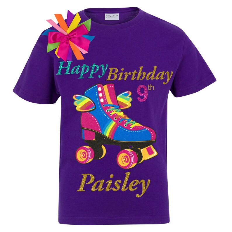 May include: Purple t-shirt featuring a rainbow roller skate graphic, the words "Happy Birthday 9th" and the name "Paisley" in gold glitter.