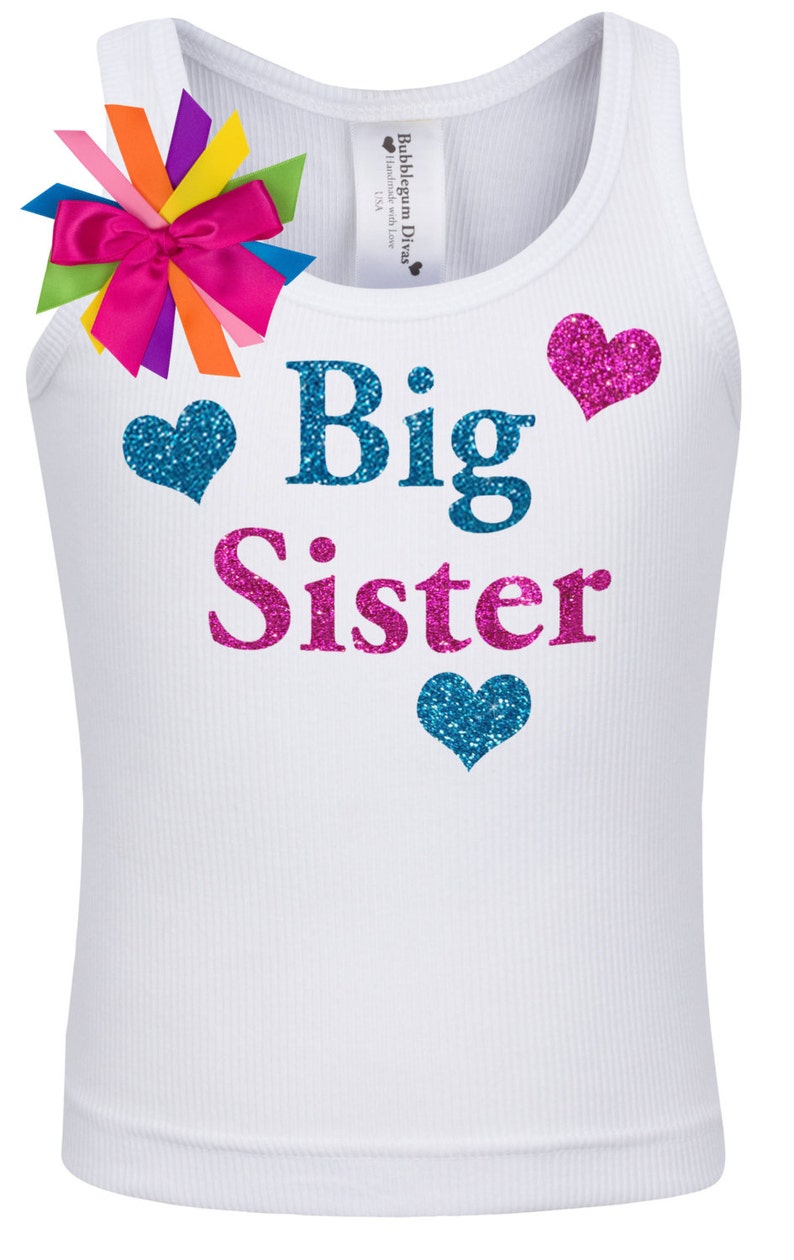 May include: White tank top with the words "Big Sister" in blue and pink glitter lettering. There are three glitter hearts, two blue and one pink, on the shirt.