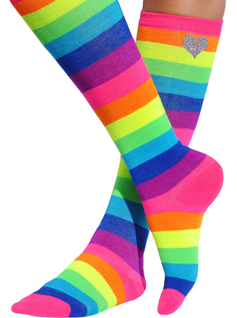 May include: A pair of knee-high socks with a rainbow stripe pattern. The socks are pink, orange, yellow, green, blue, purple, and pink. One sock has a silver glitter heart on the top.