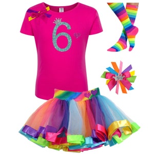 May include: A pink t-shirt with a turquoise glitter number 6 and a crown on top. The shirt is paired with a rainbow tulle skirt with a satin ribbon trim and a rainbow striped knee-high sock.