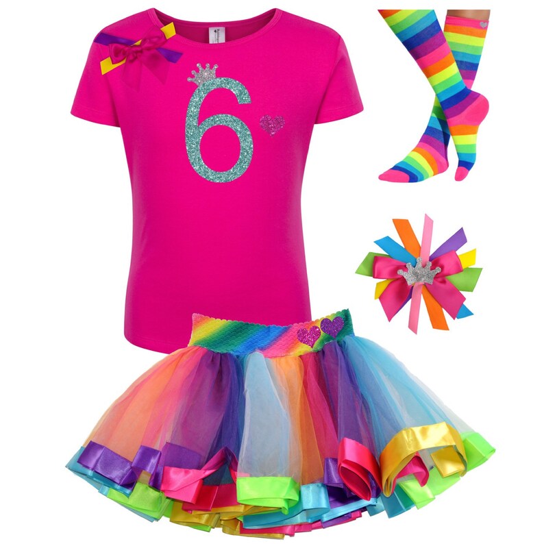 May include: A pink t-shirt with a turquoise glitter number 6 and a crown on top. The shirt is paired with a rainbow tulle skirt with a satin ribbon trim and a rainbow striped knee-high sock.