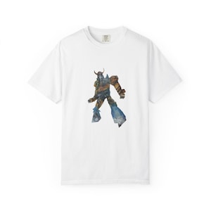 Può includere: T-shirt bianca con grafica di un guerriero nei toni del blu, marrone e oro. La t-shirt è realizzata in materiale morbido e ha un girocollo. La grafica è centrata sul davanti.