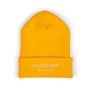May include: Mustard yellow beanie hat with the embroidered text "GOD BELIEVES IN ME" and "Jeremiah 29:11" in white. The hat is a warm, knitted hat, ideal for cold weather. The hat is a solid colour.