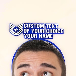 Peut inclure: Un emblème bleu et blanc avec le texte "CUSTOM TEXT OF YOUR CHOICE YOUR NAME" au-dessus de la tête d'une personne. L'emblème présente un motif d'étoile et de rayures. Le texte est en gras, police sans empattement.