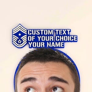May include: A blue and white emblem with the text "CUSTOM TEXT OF YOUR CHOICE YOUR NAME" above a person's head. The emblem has a star and stripes design. The text is in a bold, sans-serif font.
