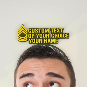 Puede incluir: Un parche de estilo militar verde oliva y amarillo con el texto "CUSTOM TEXT OF YOUR CHOICE YOUR NAME". El parche está encima de la cabeza de una persona. El parche tiene una insignia amarilla.