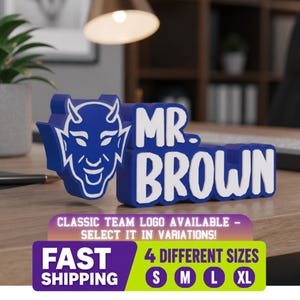 May include: A blue and white 3D sign featuring a devil mascot graphic and the text MR. BROWN. The sign includes additional text stating CLASSIC TEAM LOGO AVAILABLE - SELECT IT IN VARIATIONS! FAST SHIPPING and 4 DIFFERENT SIZES S M L XL.