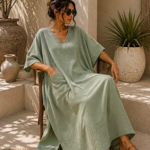 May include: A sage green midi-length kaftan dress with a V-neckline, short wide sleeves, and side pockets. The fabric has a textured, crinkled appearance. The text "TrendTrunkSyndicate" is visible in the bottom left corner of the image.