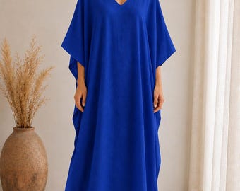 May include: A floor-length, vibrant royal blue kaftan dress featuring a V-neckline and wide, loose-fitting sleeves. The garment has a relaxed, flowing silhouette that extends to the ankles, crafted from a solid-colored fabric with a subtle texture.