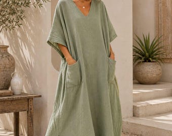 May include: A sage green maxi dress featuring a V-neckline, short wide sleeves, and two large front patch pockets. The garment has a loose, flowing silhouette with side slits at the hem. The text TrendTrunkSyndicate is visible at the bottom.