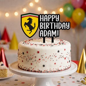 Può includere: Una torta rotonda bianca sormontata da un topper nero a forma di scudo giallo con un cavallo nero rampante e il testo HAPPY BIRTHDAY ADAM! in lettere nere. La torta è decorata con piccole codette a forma di stella rosse e nere.