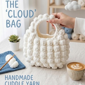May include: A handmade white cloud bag with a rounded handle and a textured, puffy design. The bag is held by a person's hand. The text "THE 'CLOUD' BAG" and "HANDMADE CUDDLE YARN" are visible. A small succulent plant and a cup of coffee are also in the image.