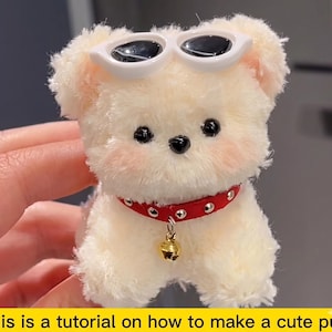 Può includere: Un cucciolo di peluche color crema con occhiali da sole bianchi e un collare rosso con una campana dorata. Il cucciolo ha occhi neri e guance rosa. L'immagine include il testo: "This is a tutorial on how to make a cute puppy."