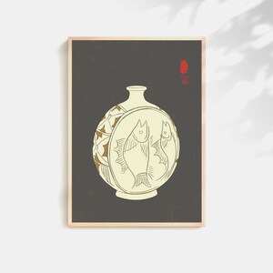 May include: A framed print featuring a cream-colored vase with a round body and a narrow neck. The vase has a circular design with two fish illustrations. The background is dark gray, and the frame is light brown.