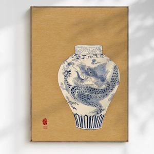 May include: A framed print of a white and blue ceramic vase with a dragon design. The vase has a detailed illustration of a dragon in blue against a white background. The frame is a light brown color.