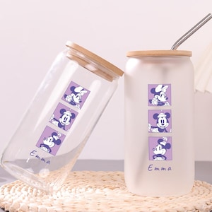 Puede incluir: Dos vasos de vidrio con tapas de bamb&uacute; y pajitas de metal. Uno es transparente y el otro es esmerilado. Ambos presentan un gr&aacute;fico vertical morado con tres personajes de rat&oacute;n y el nombre Emma impreso en cursiva en la parte inferior.