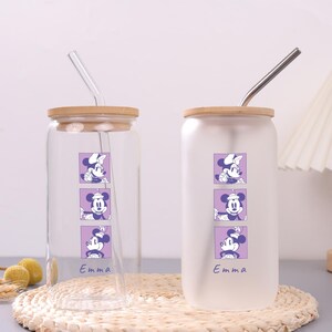 Puede incluir: Dos vasos de vidrio con tapas de bamb&uacute; y pajitas. Uno es transparente, el otro es esmerilado. Cada uno presenta un gr&aacute;fico vertical de tres cuadrados morados con personajes de rat&oacute;n y el nombre Emma en cursiva bajo el dise&ntilde;o.