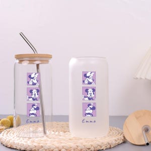 Puede incluir: Dos vasos de cristal, uno transparente y otro esmerilado, con tres gr&aacute;ficos cuadrados morados apilados de un rat&oacute;n de dibujos animados y el nombre Emma en azul. Ambos vasos incluyen una tapa de bamb&uacute; y una pajita de metal.