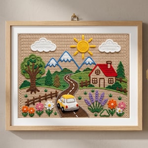 May include: A framed crochet wall art piece measuring 30.5 cm x 23 cm, featuring a landscape with a yellow car on a road, a red-roofed house, green trees, blue mountains, a yellow sun, white clouds, and colourful flowers on a tan background.