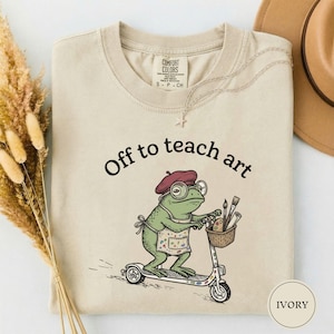 Off to Teach Art Shirt, Funny Frog Art Teacher Tee, Frog on Scooter Paint Gift, Women Art Educator Shirt, Frog Lover Tee, Funny Art Teacher Ivory