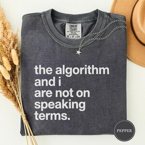 May include: A white ceramic mug with a black handle and the text "But First, Coffee" in a handwritten style. The mug is on a white surface. The mug is likely 11 ounces.