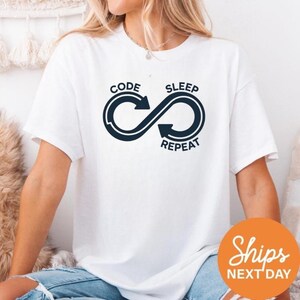 May include: A white ceramic mug with a black handle and the text "But First, Coffee" in a bold, black font. The mug is set against a blurred background, highlighting its clean design.