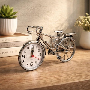 May include: A silver-colored bicycle-shaped clock with a white clock face and black numbers. The clock has a quartz movement and a red second hand. The bicycle clock is a decorative item.