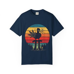 May include: Navy blue t-shirt featuring a graphic of a rooster smoking a joint, with a cannabis leaf and smoke clouds. The design is set against a retro sunset backdrop with a pi symbol. The shirt is a casual wear item.