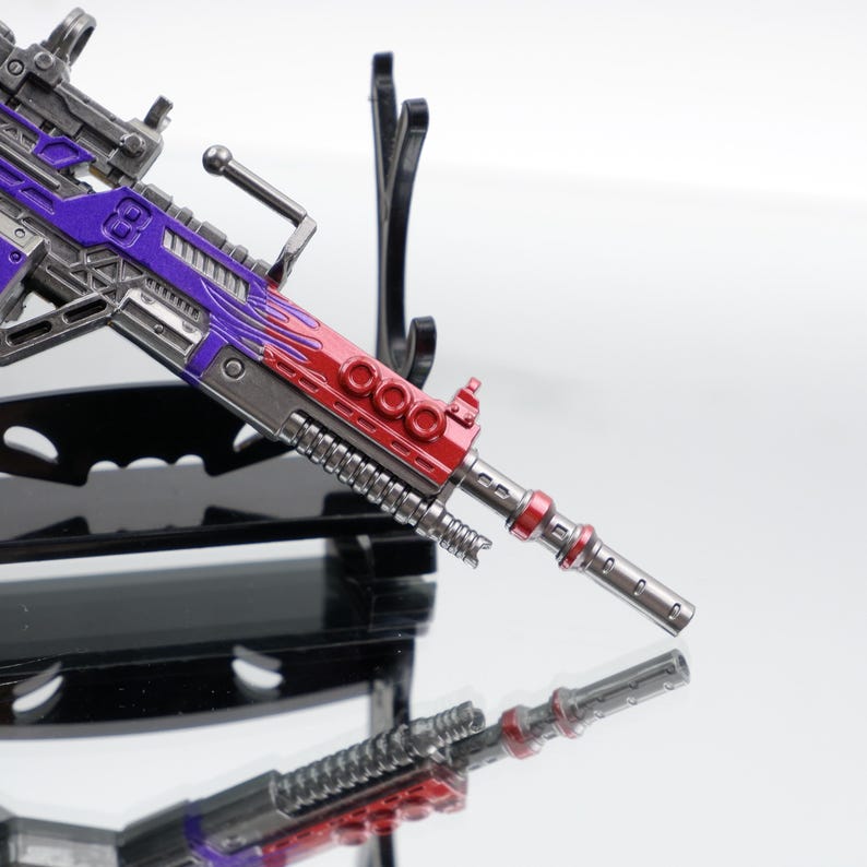 Puede incluir: Un rifle de juguete detallado con un acabado met&aacute;lico, que presenta una combinaci&oacute;n de colores vibrantes. El rifle tiene un ca&ntilde;&oacute;n y detalles en rojo, con detalles en morado y plateado en el cuerpo. El dise&ntilde;o incluye elementos mec&aacute;nicos intrincados.