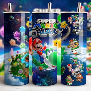 Puede incluir: Tres vasos de acero inoxidable con un diseño de Super Mario Galaxy. El diseño presenta a Mario, Yoshi y otros personajes en un fondo espacial con el logo del juego. Cada vaso tiene una pajita plateada.