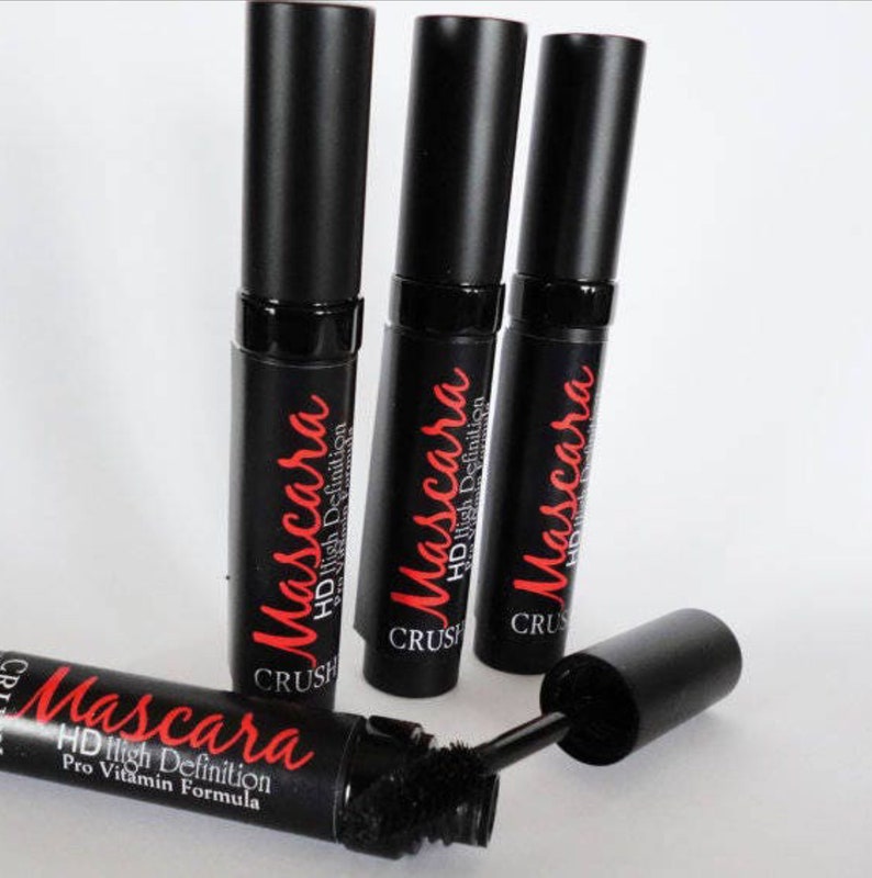 May include: Four black mascara tubes with red text that reads "Mascara HD High Definition Pro Vitamin Formula". One tube is open, revealing the brush. The mascara tubes are arranged on a white surface.