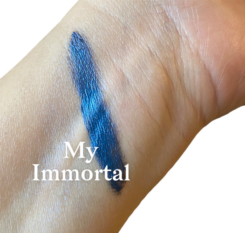 May include: A close-up of a blue eyeshadow swatch on a person's arm. The swatch is labelled "My Immortal".