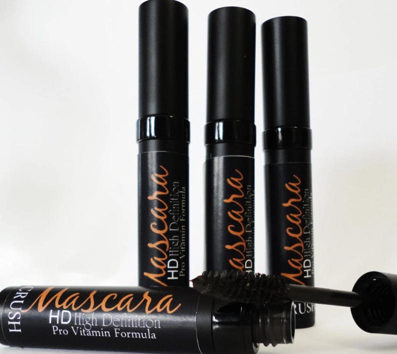 May include: Black mascara tubes with the text "Mascara HD High Definition Pro Vitamin Formula" in a copper color. One tube has the brush extended. The mascara tubes are on a white background.