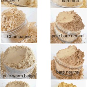 May include: A collection of ten different shades of foundation powder in small glass jars. The shades are labeled: porcelain, bare buff, champagne, pale bare neutral, pale warm beige, bare neutral, warm beige, and honey beige.