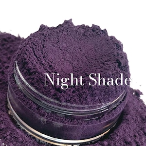 Może przedstawiać: Zbliżenie na mały szklany słoik wypełniony głębokim fioletowym proszkiem z etykietą "Night Shade".