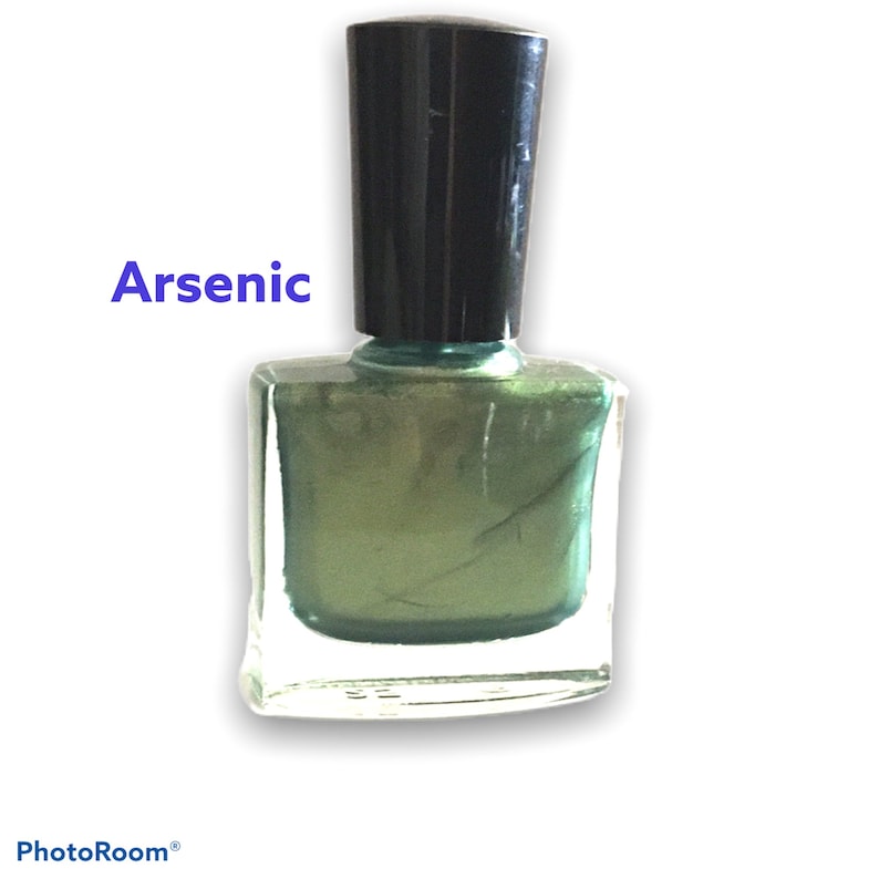 以下が含まれることがあります： 黒いキャップが付いた緑色のマニキュアボトル。ボトルには「Arsenic」とラベルが貼られています。