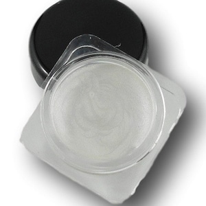 Könnte beinhalten: Ein kleiner, runder, transparenter Behälter mit einer weißen, perlmuttartigen Substanz darin. Der Behälter ist aus Kunststoff und hat einen schwarzen Deckel.