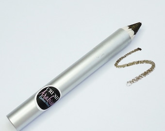 Puede incluir: Un lápiz delineador de ojos plateado con una etiqueta negra que dice "Crush Arabia Eyeliner Pencil". El lápiz está afilado y hay una línea marrón oscura dibujada sobre el fondo blanco.