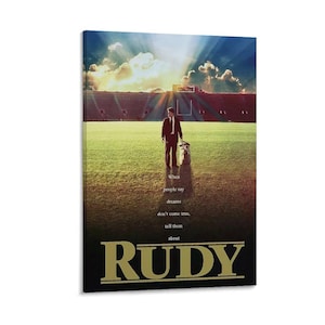 May include: A framed canvas print featuring a scene from the movie "Rudy." A man in a suit stands on a football field with a dog, with a stadium in the background. The text "When people say dreams don't come true, tell them about RUDY" is displayed.