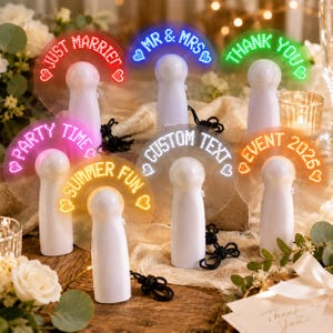 May include: Six white handheld LED fans with clear blades displaying glowing text and heart icons. The messages include JUST MARRIED, MR & MRS, THANK YOU, PARTY TIME, SUMMER FUN, CUSTOM TEXT, and EVENT 2025. Each fan features a black wrist lanyard.